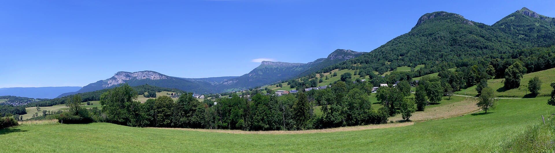 Vallon pastoral verdoyant dominé par des sommets calcaires