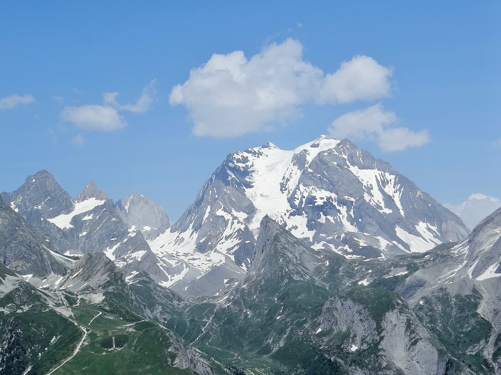 Massif enneigé rosi par le couchant au-dessus d'une plaine dorée