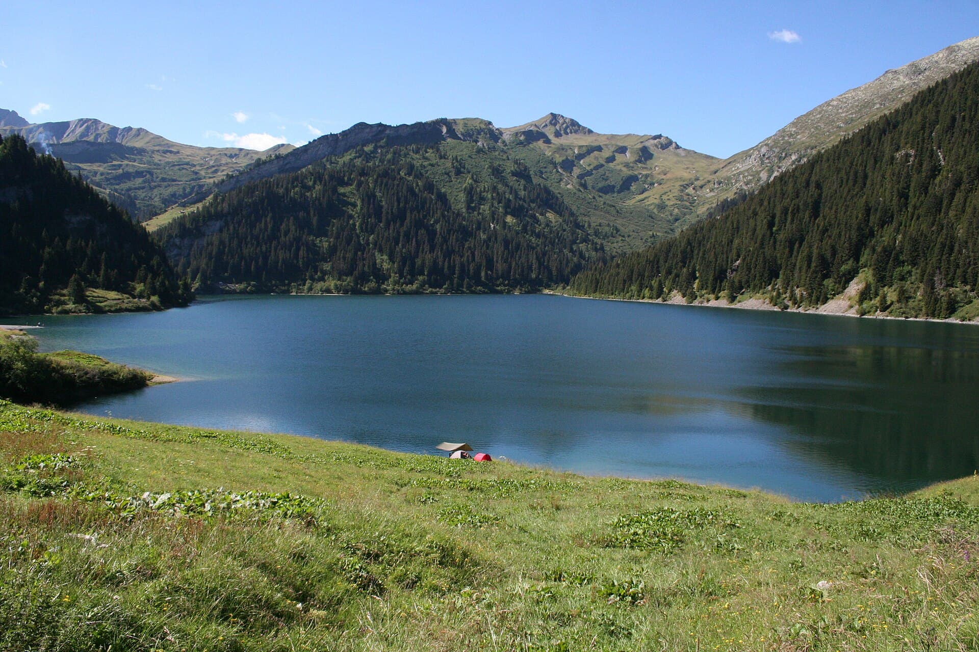 Lac de barrage turquoise entouré d'alpages