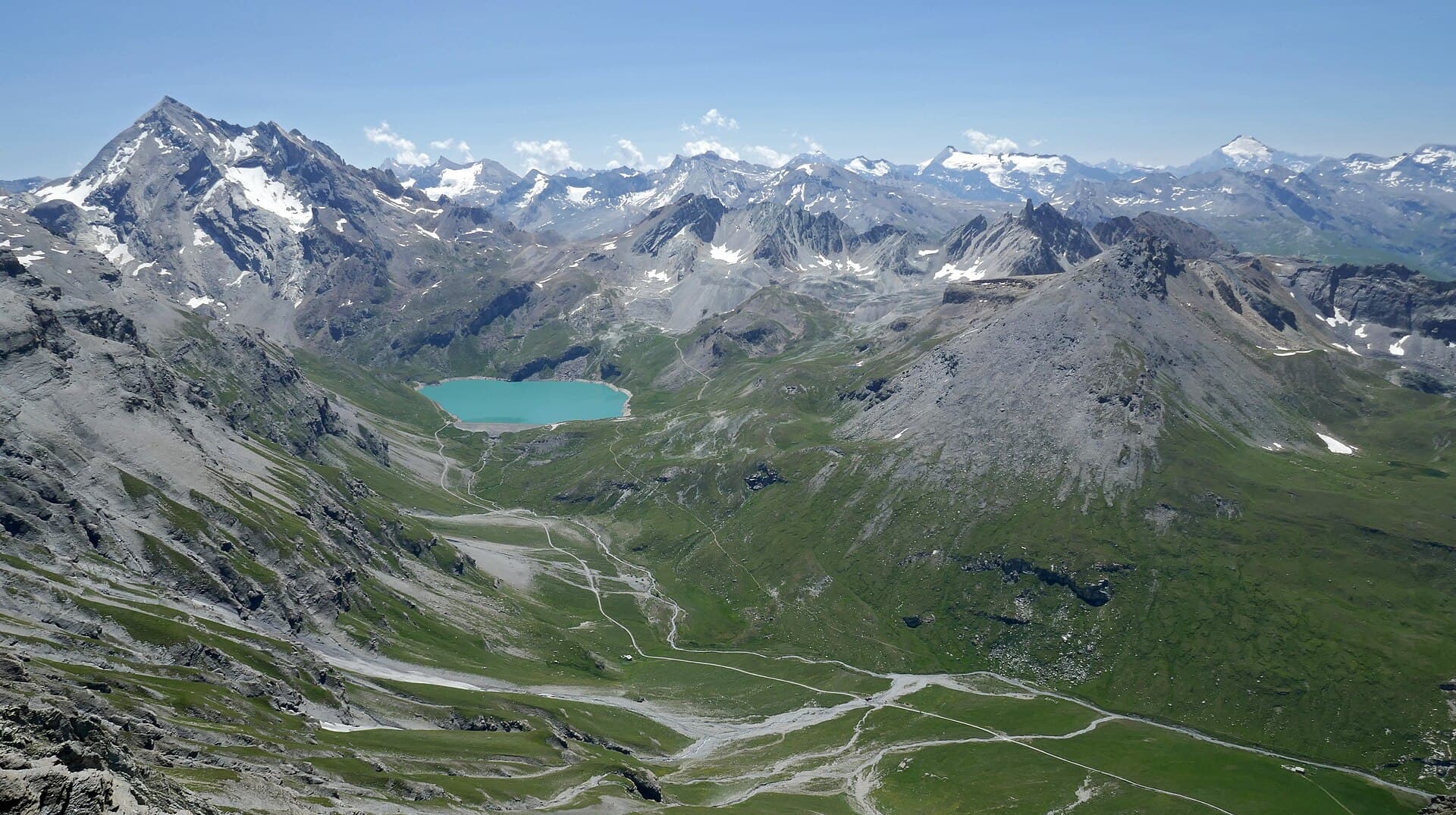 Vallon d'altitude verdoyant sous les cimes, torrent en contrebas